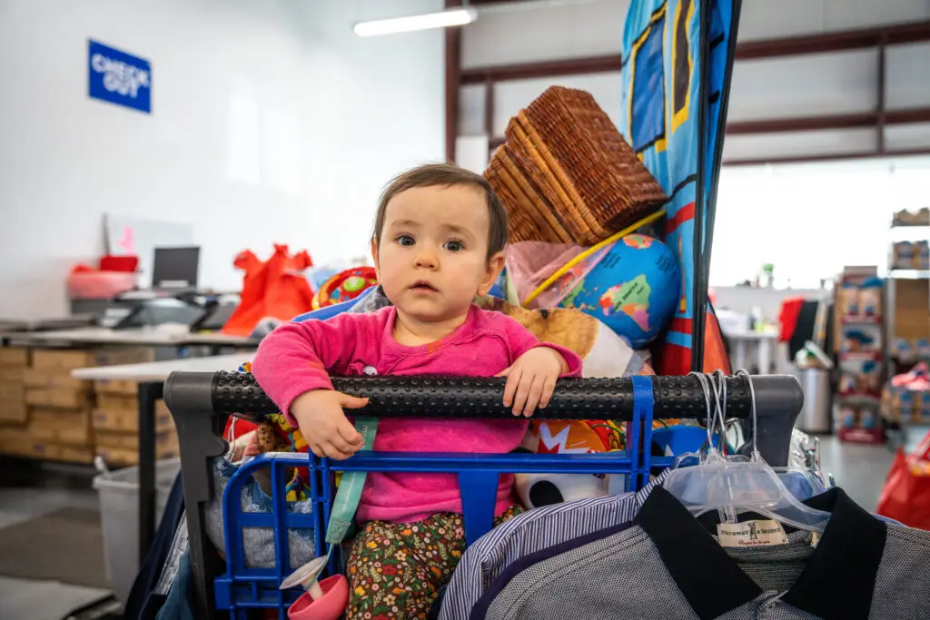 Small child sitting in a cart filled with items from the Resource Center