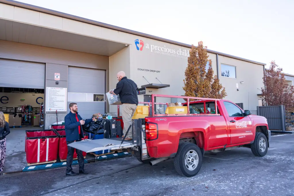 A full red truck handing over donations at the drop-off location at A Precious Child.