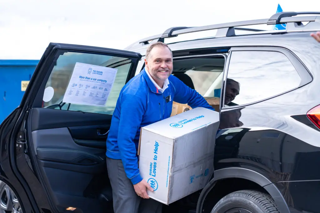 A man grabbing donation items from their vehicle collected from a Basic Needs drive.