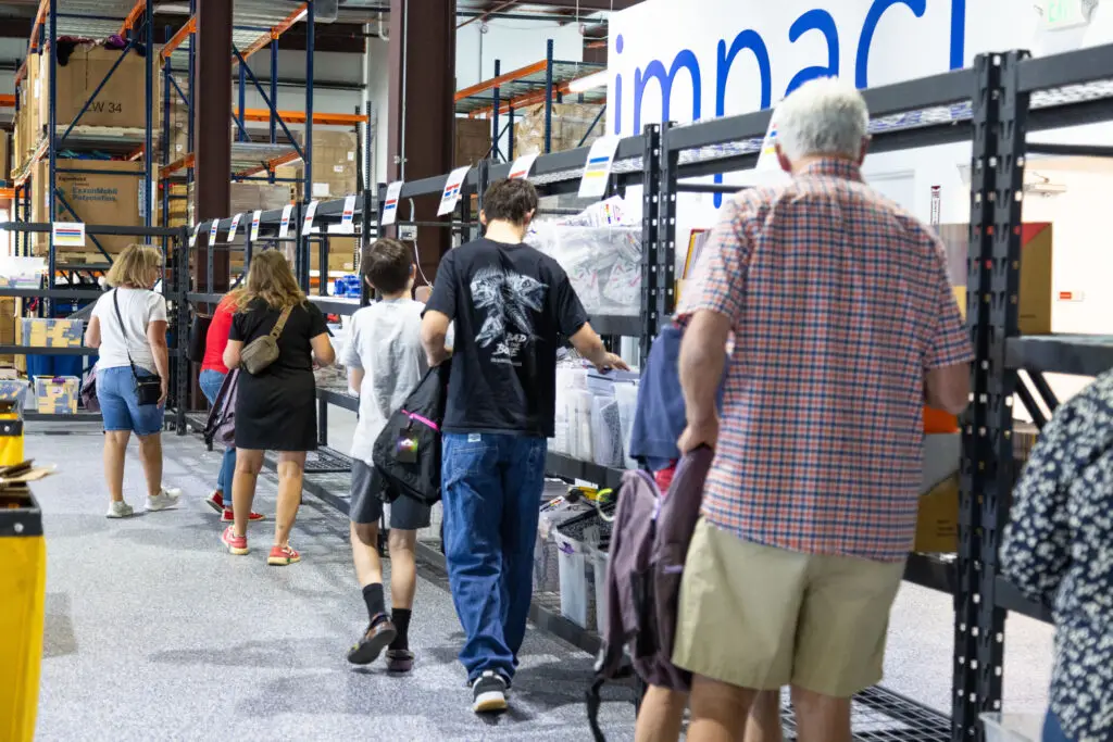 A family volunteering together and filling up backpacks with new school supplies.