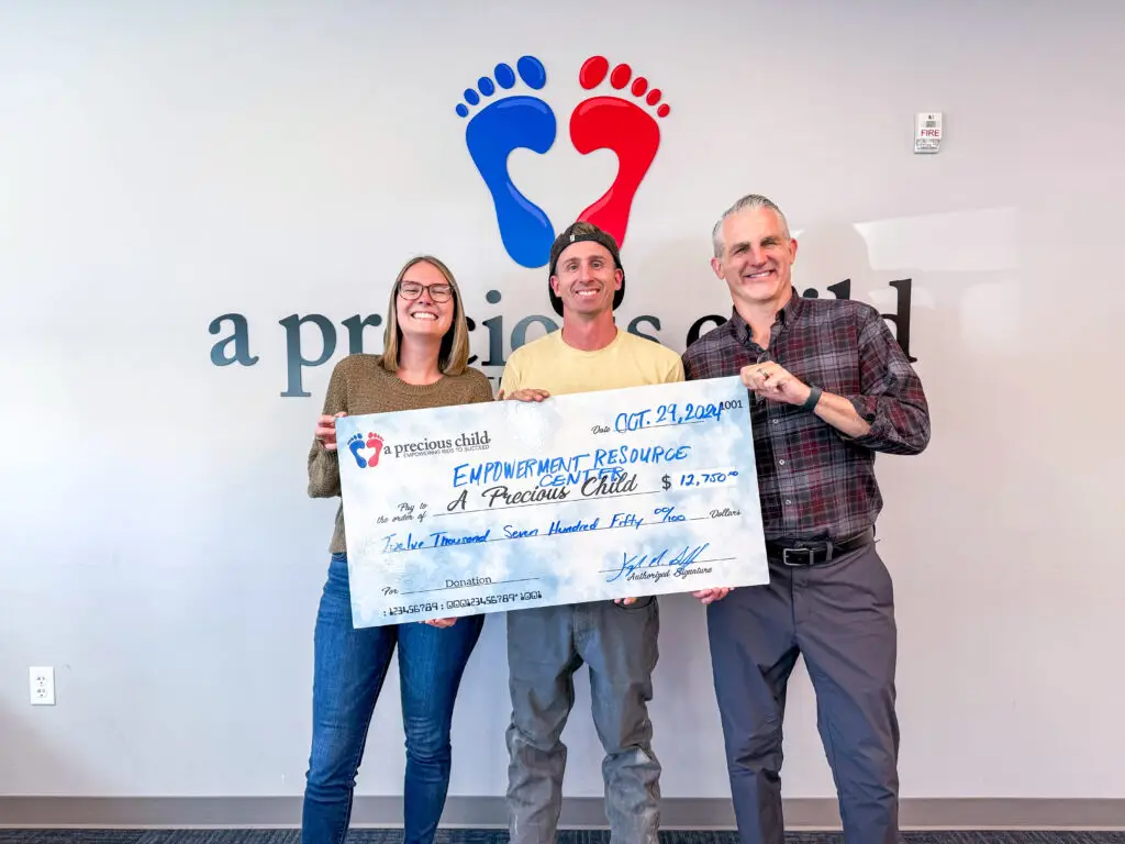 A Precious Child team standing with community members holding a donation check for A Precious Child
